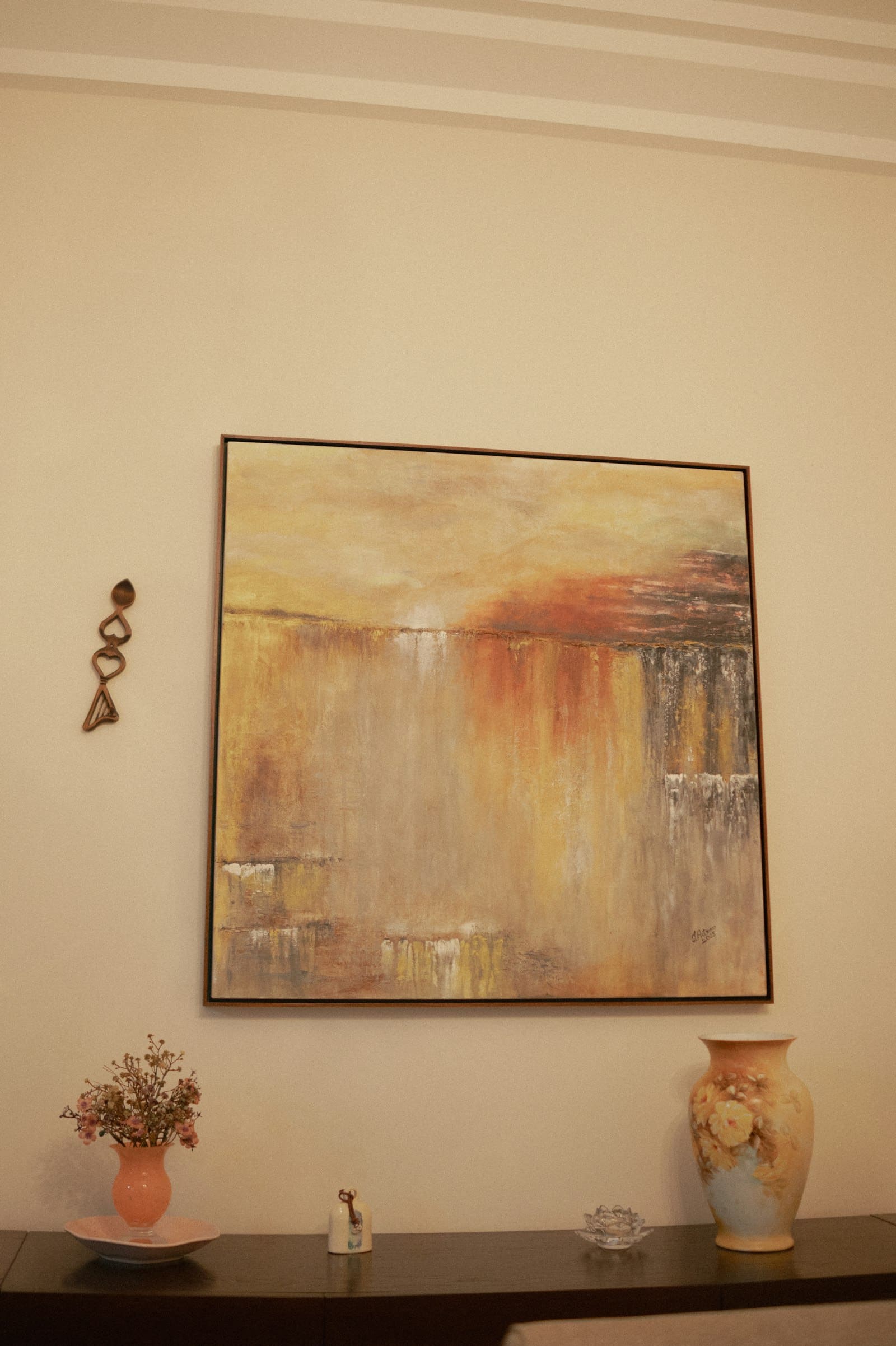 Large abstract canvas print in warm amber and rust tones above a styled console table