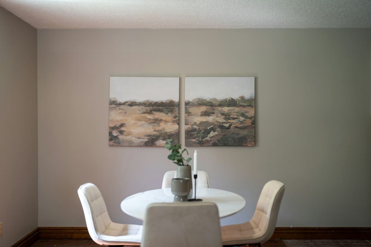 Two-panel earth-toned abstract landscape painting above a dining table