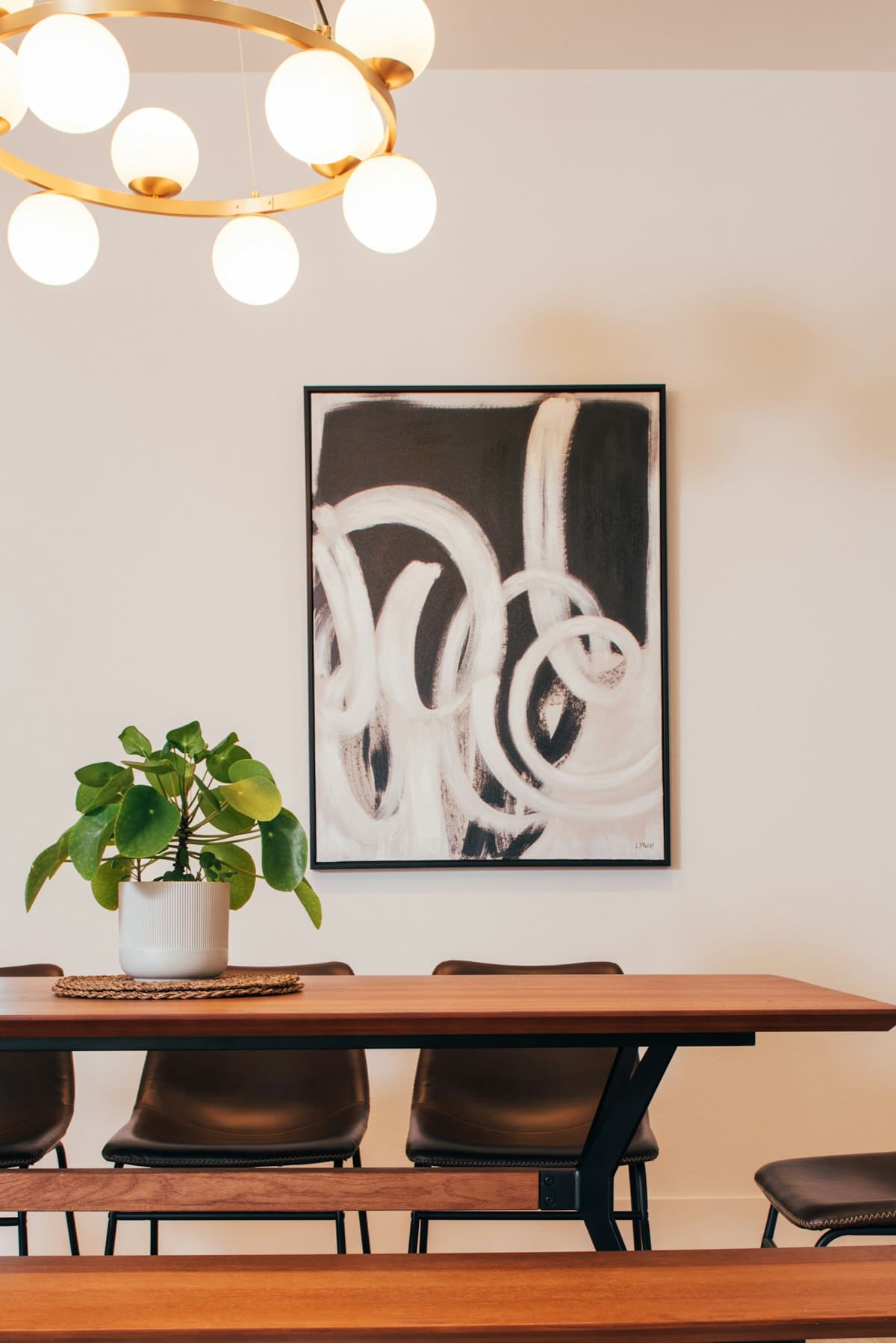 Black and white brushstroke abstract painting above a wooden dining table