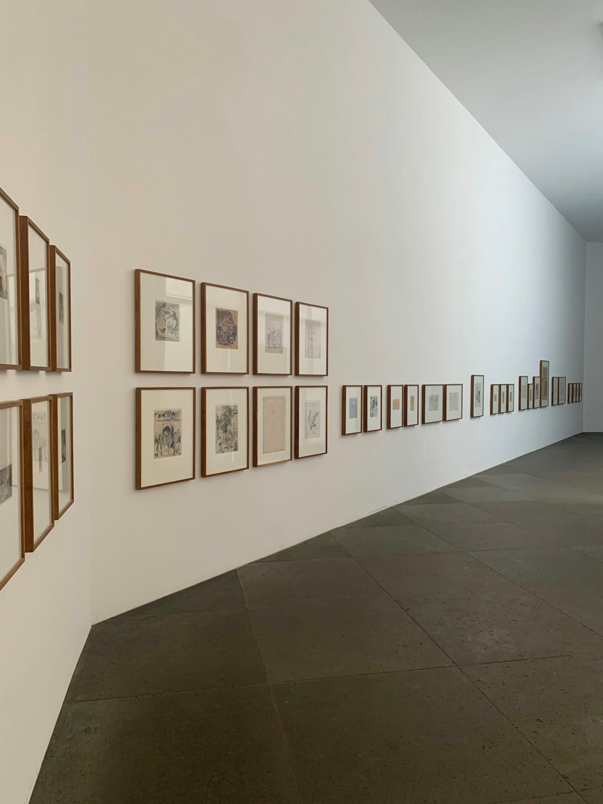 Row of small framed prints along a light gallery corridor