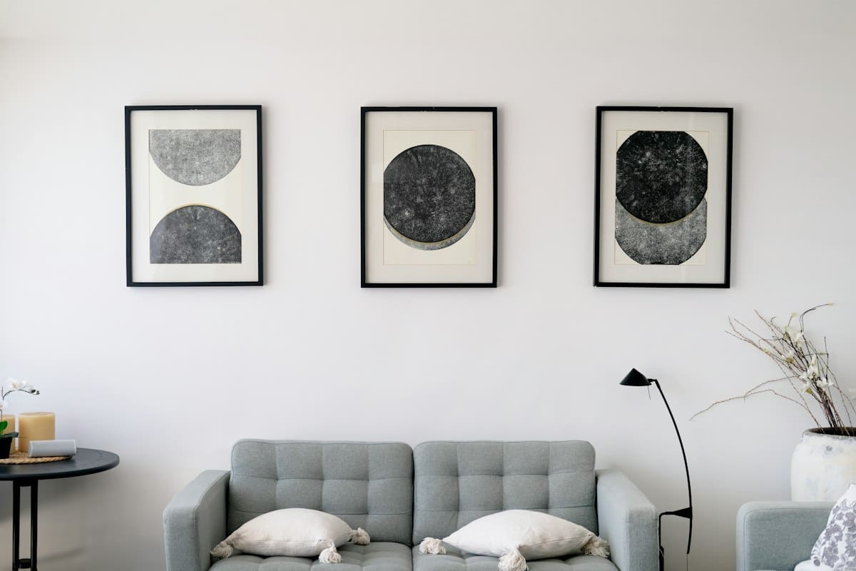 Three black and white circular abstract prints above a grey sofa