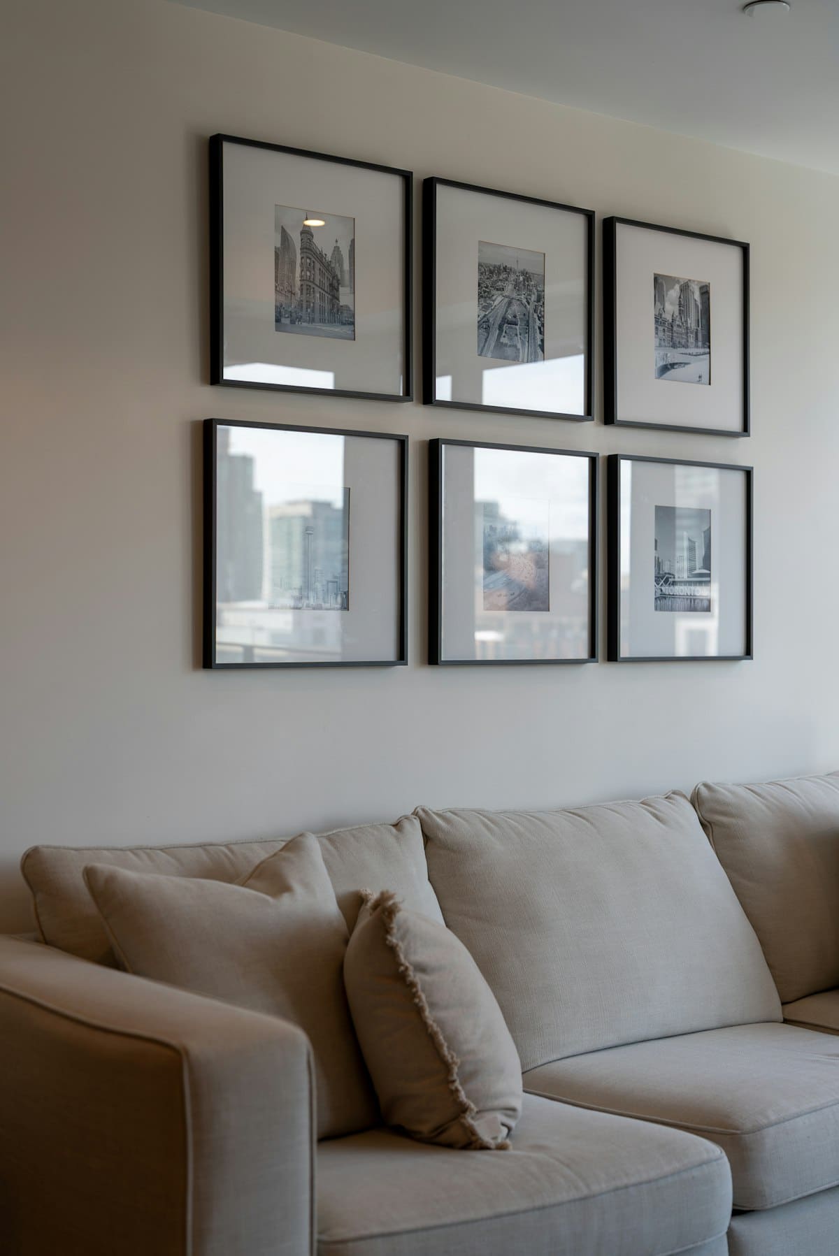 Grid of six black-and-white cityscape photographs above a sofa